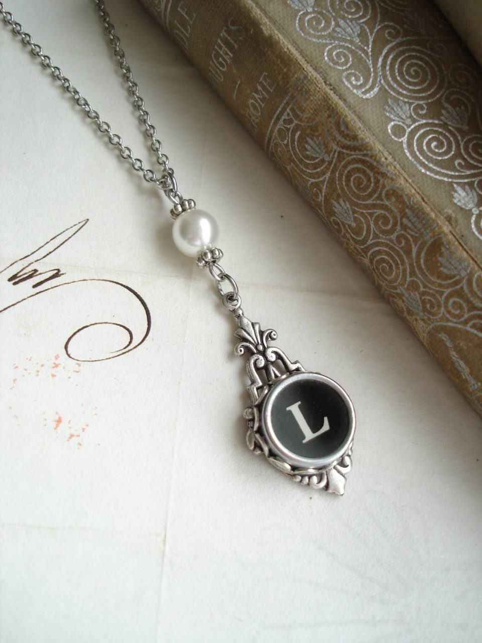 Elegant Letter L pendant on vintage typewriter key with pearl on antique paper background Wallpaper