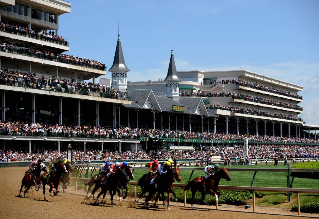 Jockeys racing thoroughbreds at 134th Kentucky Derby Churchill Downs twin spires background Wallpaper