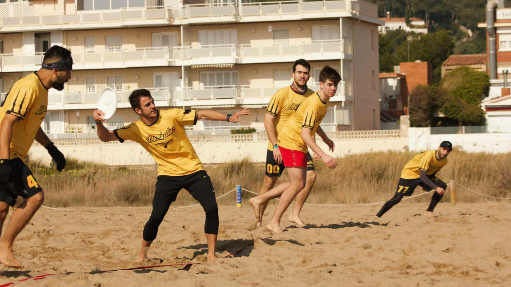Vibrant 1440p Beach Frisbee Team Action Wallpaper Background