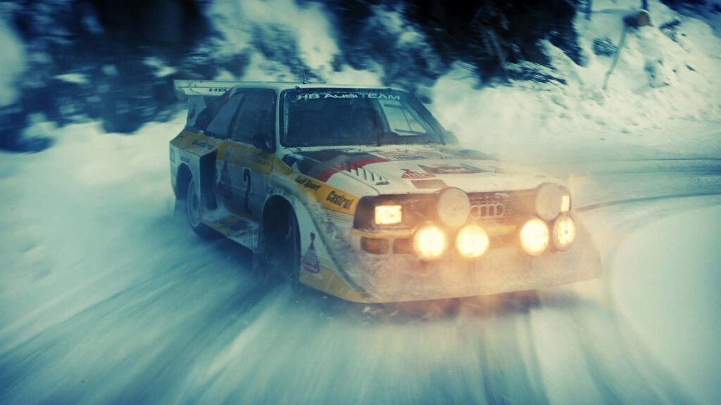 Classic rally car navigating snowy stage, headlights glowing in intense wintry backdrop Wallpaper