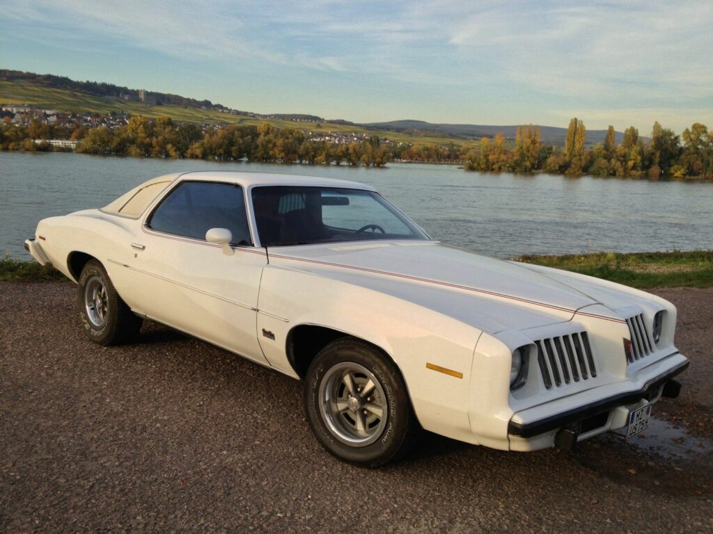 1975 Pontiac Grand Am in Serene Riverside Setting - Vintage Wallpaper
