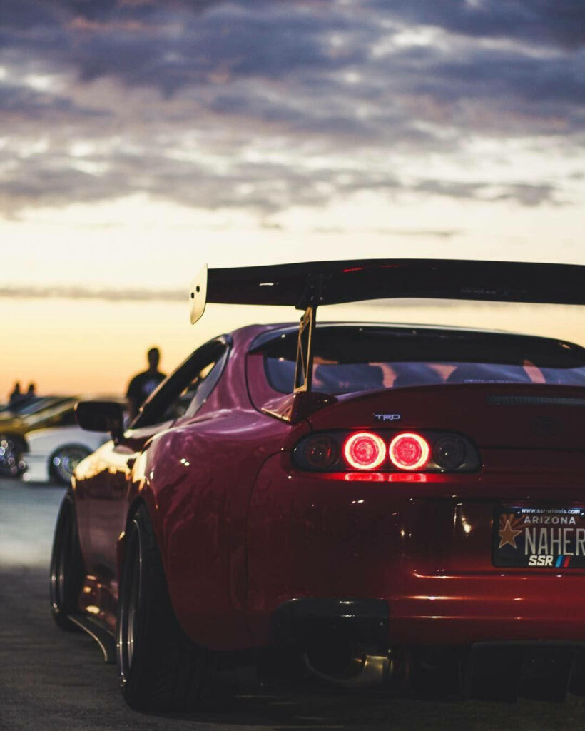 1998 Toyota Supra Mk4 rear with glowing taillights and spoiler under dramatic evening sky wallpaper
