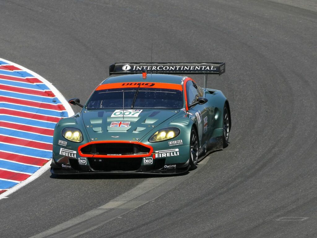 2005 Aston Martin DBR9: Sleek Green Racing Car on Asphalt Track Wallpaper