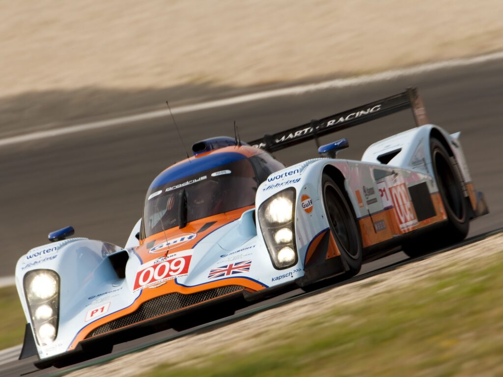 2009 Aston Martin LMP1 Race Car on Grass Track: Sleek and Aerodynamic Wallpaper