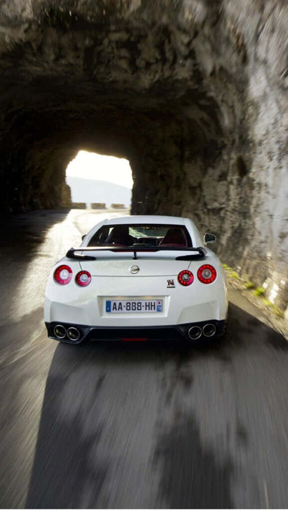 2011 Nissan R35 GTR speeding through rocky tunnel showcasing sleek rear design wallpaper