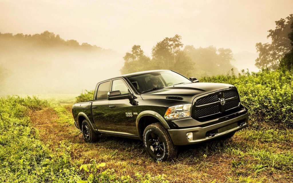 Black 2013 RAM 1500 pickup truck parked on grassy trail with lush greenery and morning mist Wallpaper