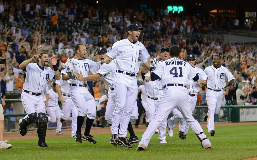 2013 Detroit Tigers team celebrating win on field with cheering fans in lively stadium wallpaper