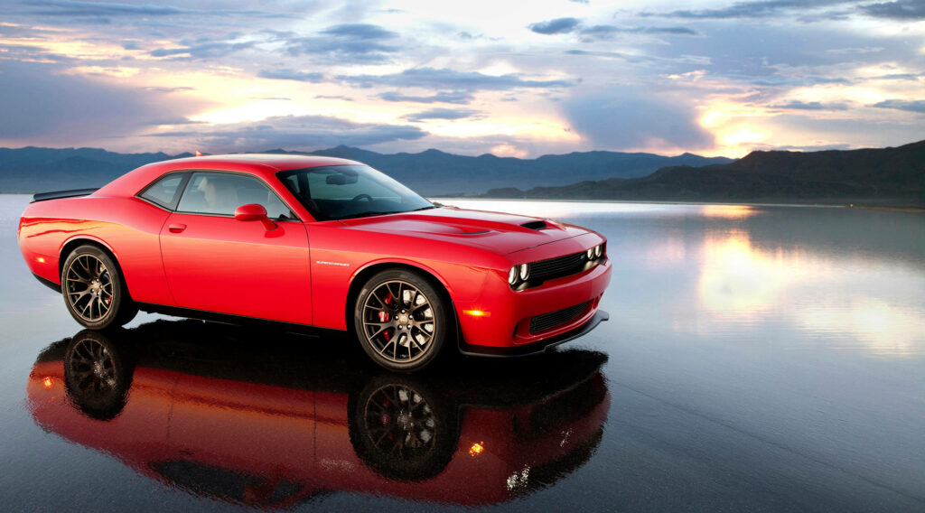 Red 2015 Dodge Challenger SRT muscle car by lakeside at sunset with dramatic clouds and mountains Wallpaper