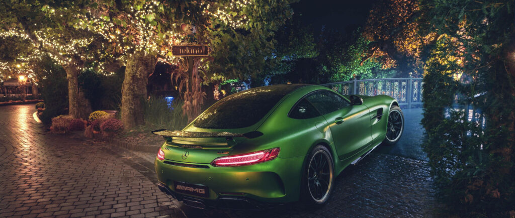 2018 Mercedes AMG GTR green back view on cobblestone path with warm decorative lights at night Wallpaper