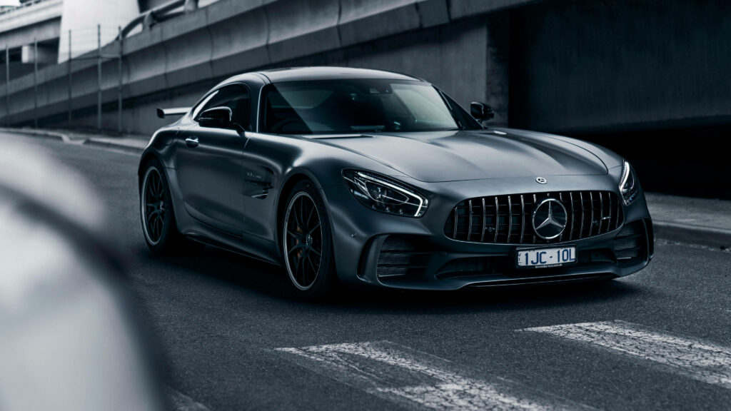 2018 Mercedes AMG GT R in motion on urban road showcasing aggressive front and track stance Wallpaper