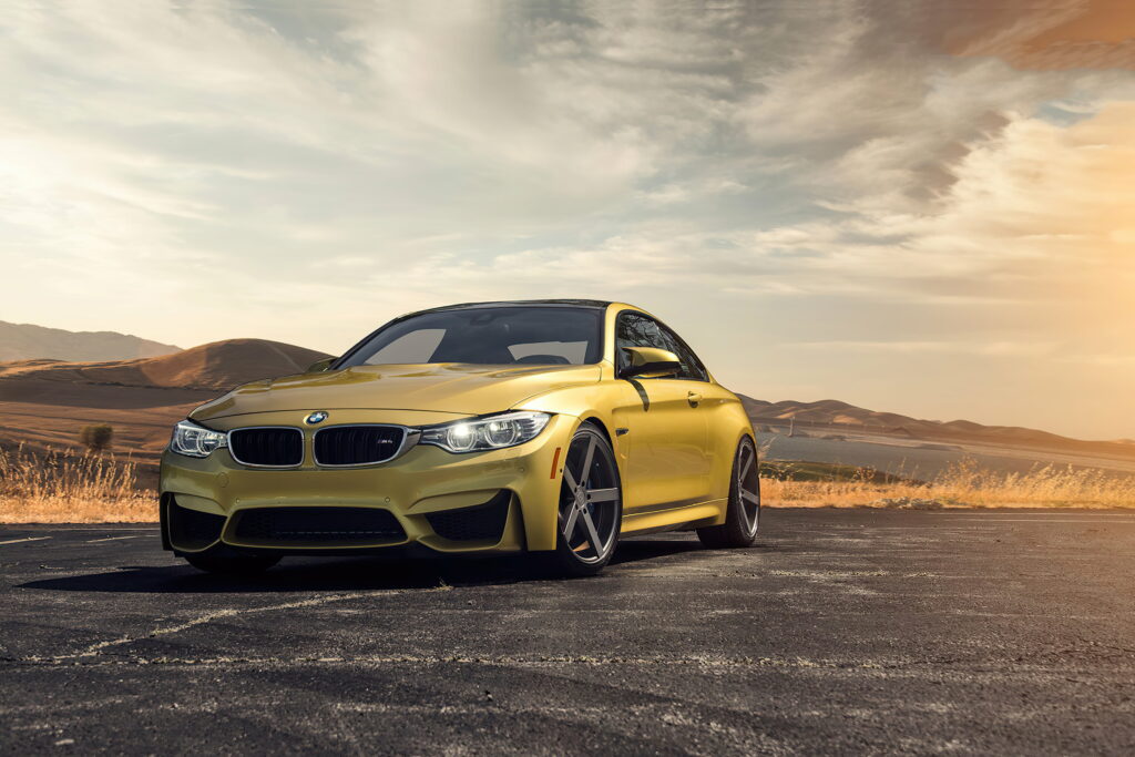 4K wallpaper of metallic yellow 2020 BMW M4 sports coupe in golden hour arid landscape