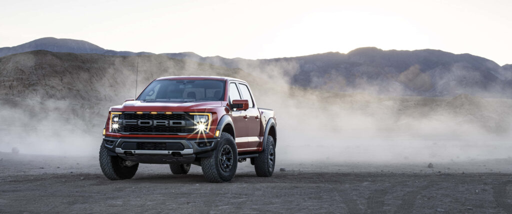 2020 Ford F150 Raptor driving through dusty desert showcasing rugged off-road truck design Wallpaper