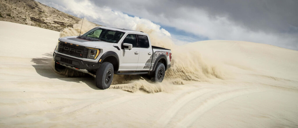 2023 Ford F150 Raptor R racing on sandy dunes showcasing rugged off-road performance wallpaper