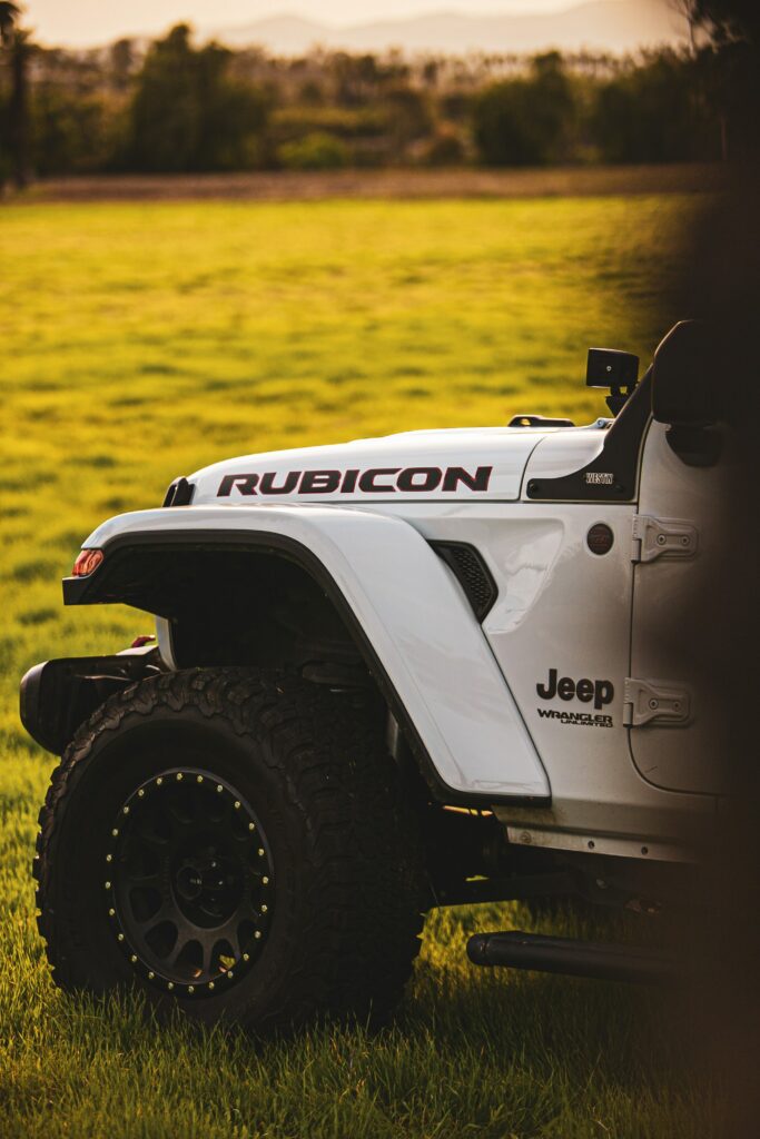 Stunning Side View of Jeep Wrangler Rubicon in Lush Green Field Wallpaper