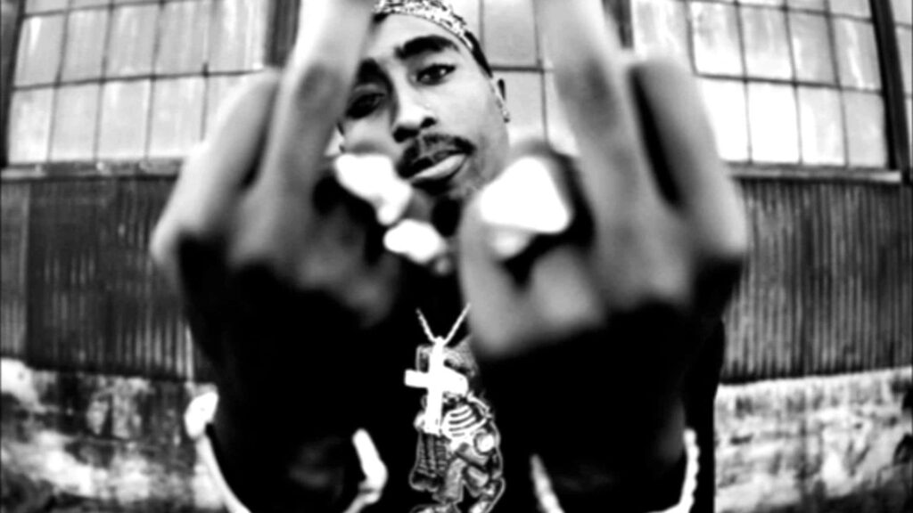 Rebel with Attitude: 2Pac Flaunts Defiance in Captivating Backdrop Wallpaper