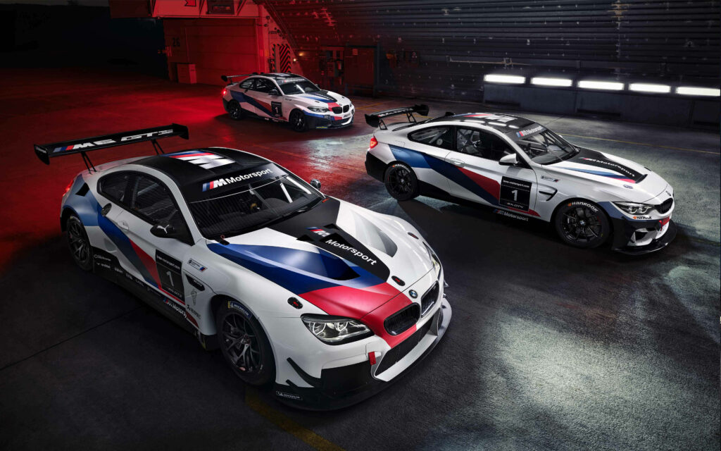 4k wallpaper of three high performance BMW racing cars in white blue and red under dramatic lighting
