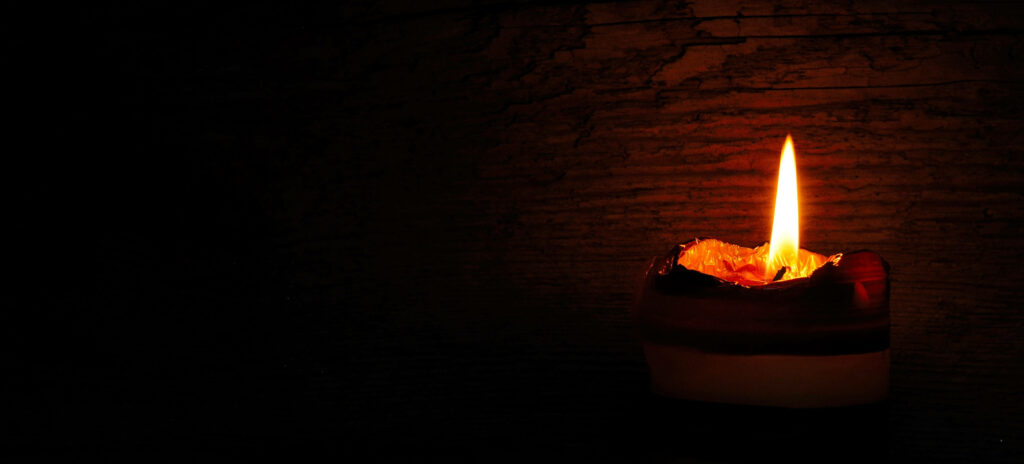 Single candle glowing warmly on rustic wooden background 4K wallpaper peaceful ambiance