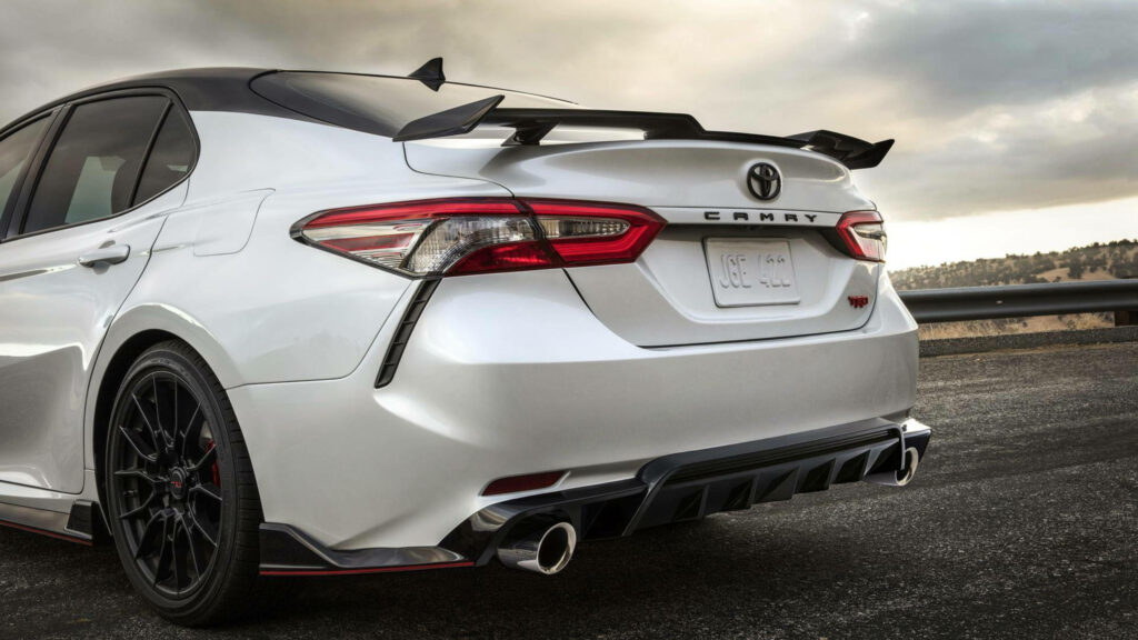 Rear view of sleek white Toyota Camry with spoiler and dual exhaust in scenic 4K wallpaper