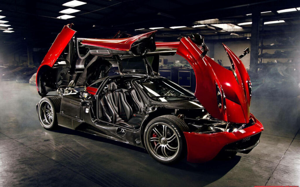 Red Pagani BC with gullwing doors open showing luxury interior in dramatic lighting garage Wallpaper