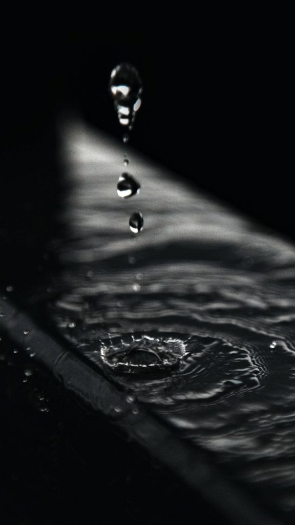 4k Ultra HD dark phone wallpaper of falling water droplets with ripples in monochrome minimal design