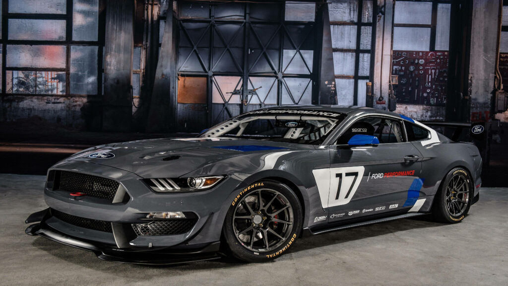 Sleek Mustang GT4 race car in 4K Ultra HD with bold graphics and modern industrial backdrop Wallpaper
