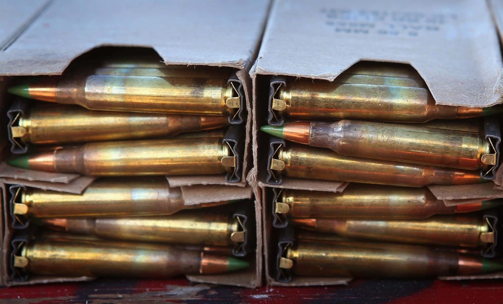 Close-up of 5.56mm NATO M855 rifle cartridges green tip bullets and brass casings wallpaper