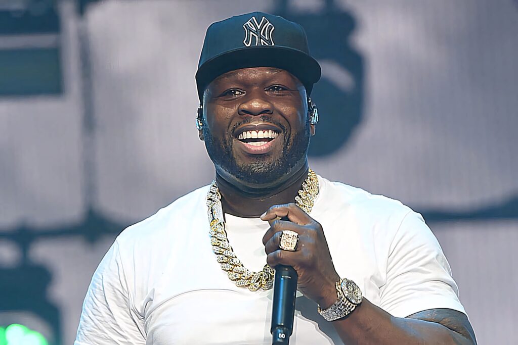 50 Cent performing live on stage in white t-shirt black cap and gold chains high energy rapper Wallpaper