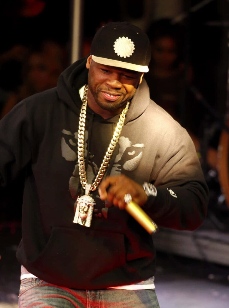 50 Cent performing on stage wearing hoodie gold chains and cap iconic rapper business mogul wallpaper