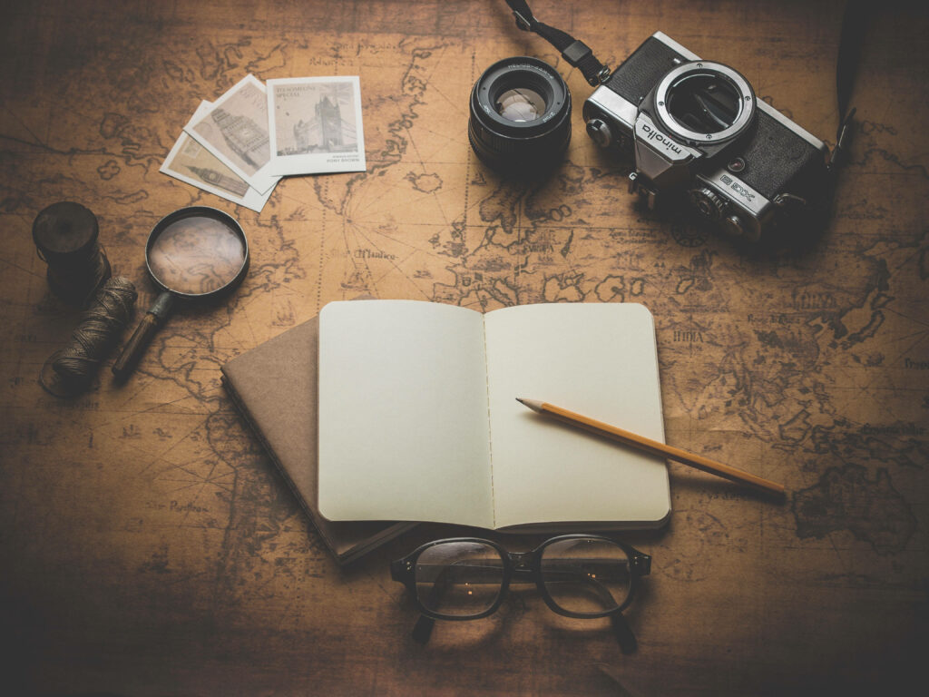 Exploring the World: Weekend Travel Planning with Notebook, Camera, and Map on Wooden Table Wallpaper