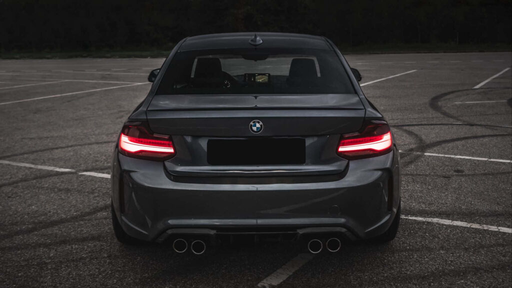 1920x1080 M Series Wallpaper featuring the Seductive Rear of a Sleek Black BMW M3, Aglow with Fiery Red Tail Lights