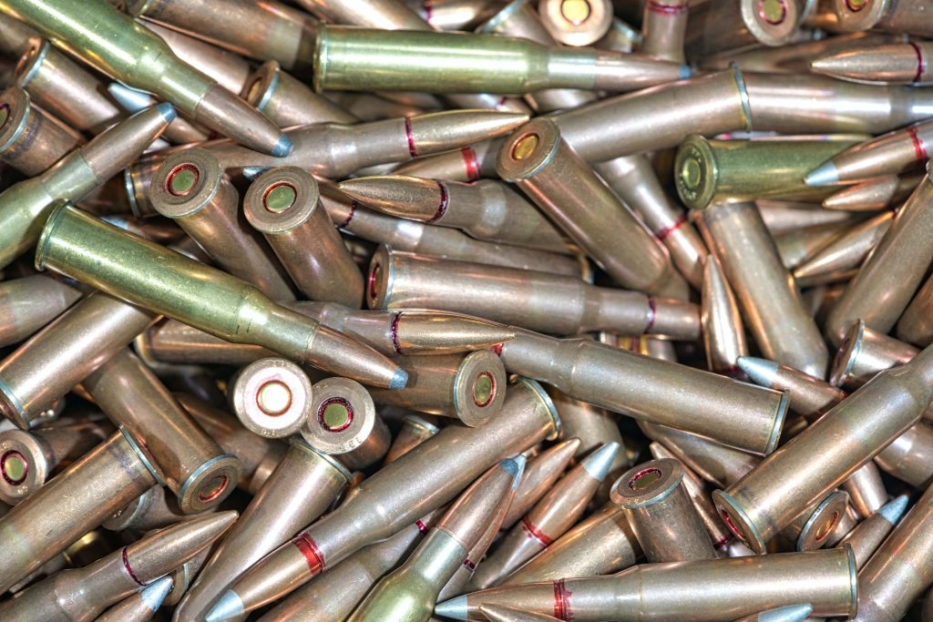 Close-up of 7.62x39mm rifle cartridges with red sealant on primers and bullet tips in pile Wallpaper