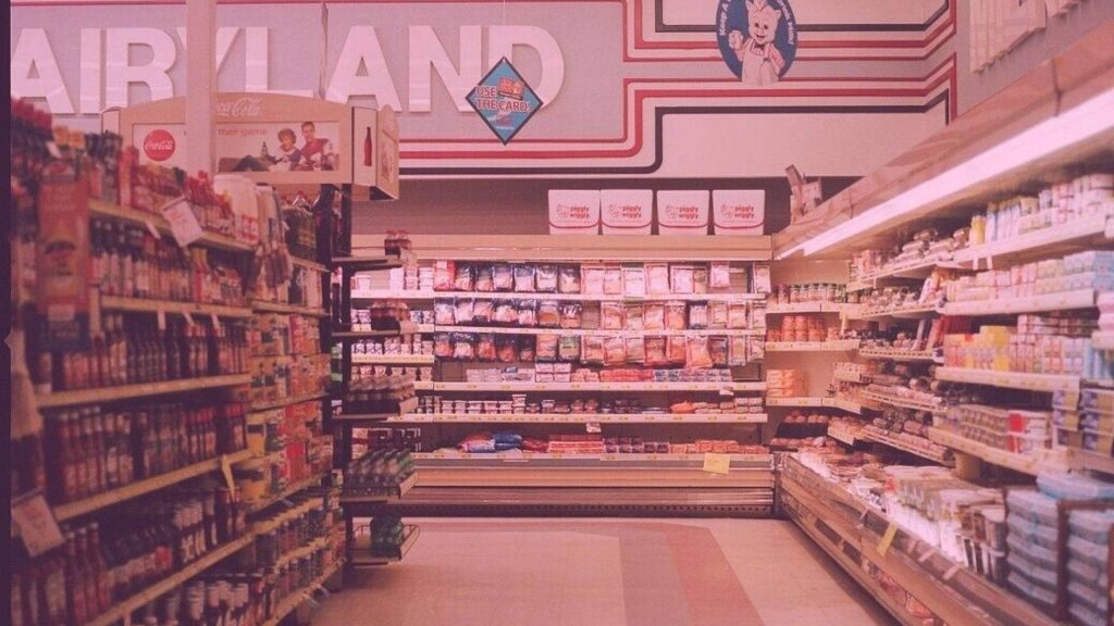 Retro 90s grocery store aisle with Piggly Wiggly and vintage Coca-Cola signs wallpaper background