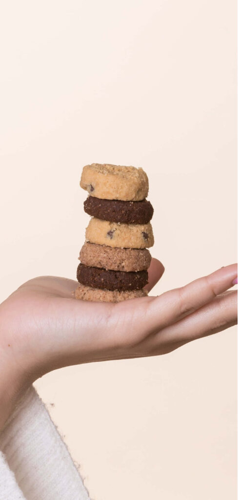 Mini Butter Cookies Embracing Delicate Fingers on a Neutral Canvas Wallpaper