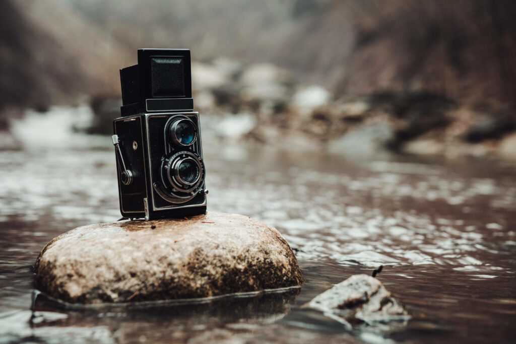 Capturing Timelessness: Vintage Box Camera poised at Brook's Stone Block Wallpaper