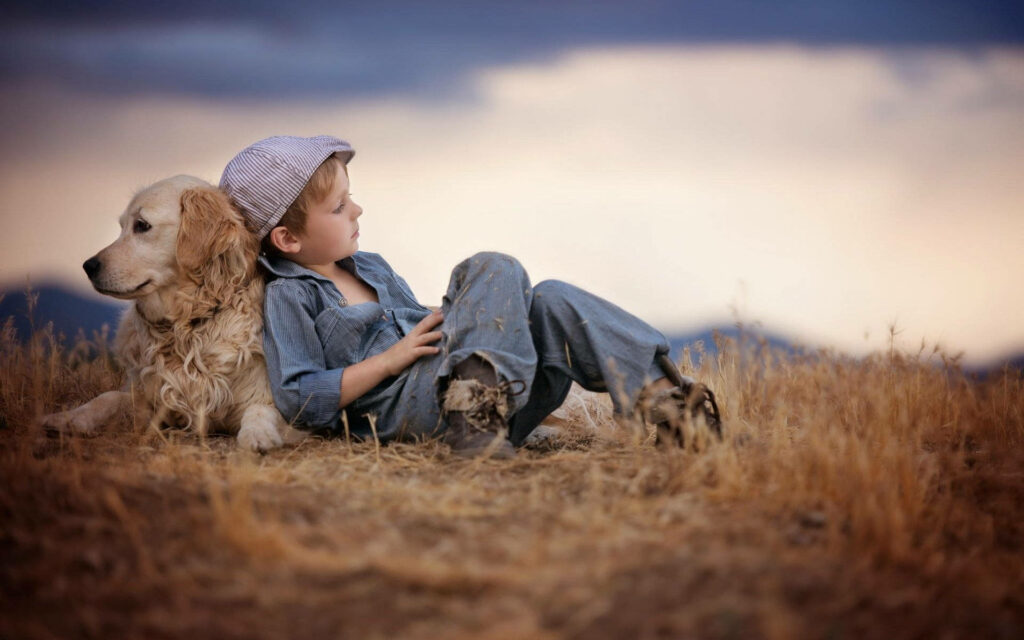 A Touching Portrait of a Loyal Friendship: Adorable Boy and His Dog's Charming Bond Amidst a Serene Meadow Wallpaper