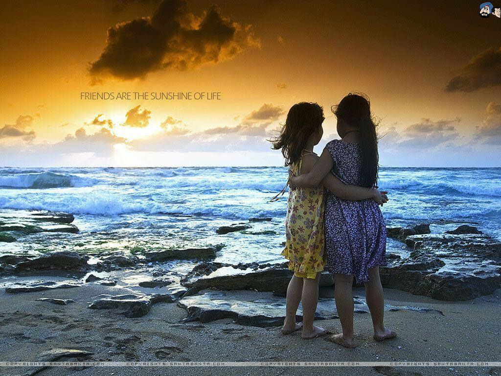 Forever Friends: Unposed Snapshot of Young Girls Bonding at the Beach Wallpaper