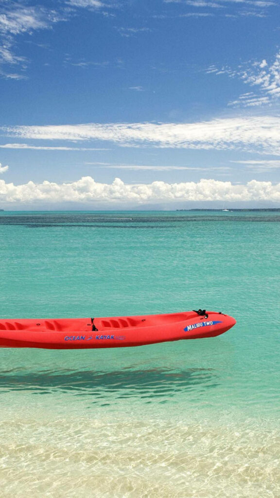 Serene Malibu Waves: Vibrant Orange Kayak Gliding on the Coastal Waters Wallpaper
