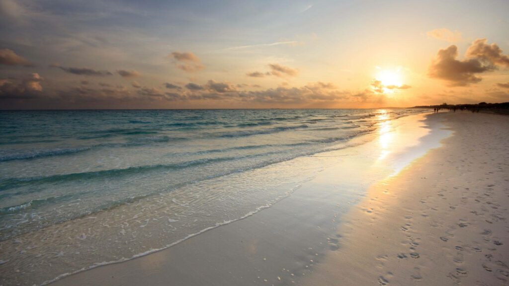 Serene Sunrise Above A Tranquil Bluish Beach with Gentle Ocean Waves - Captivating Coastal Sunrise Wallpaper