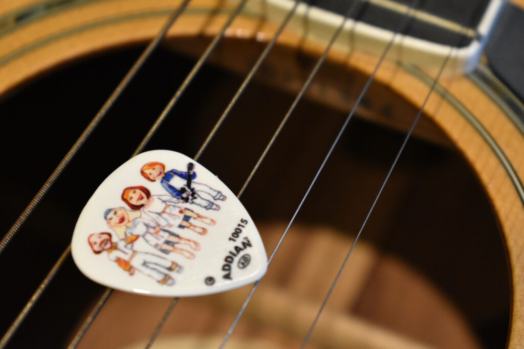 Close-up guitar with pick and cartoon ABBA illustrations music wallpaper background design