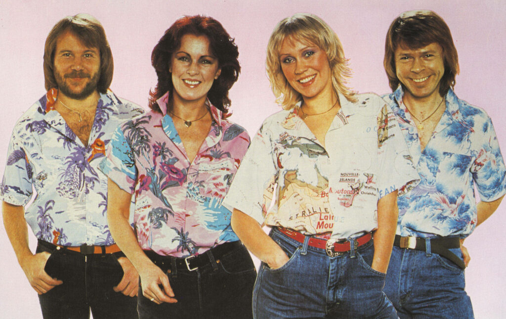 ABBA group wearing vibrant Hawaiian shirts smiling on soft pink background wallpaper background