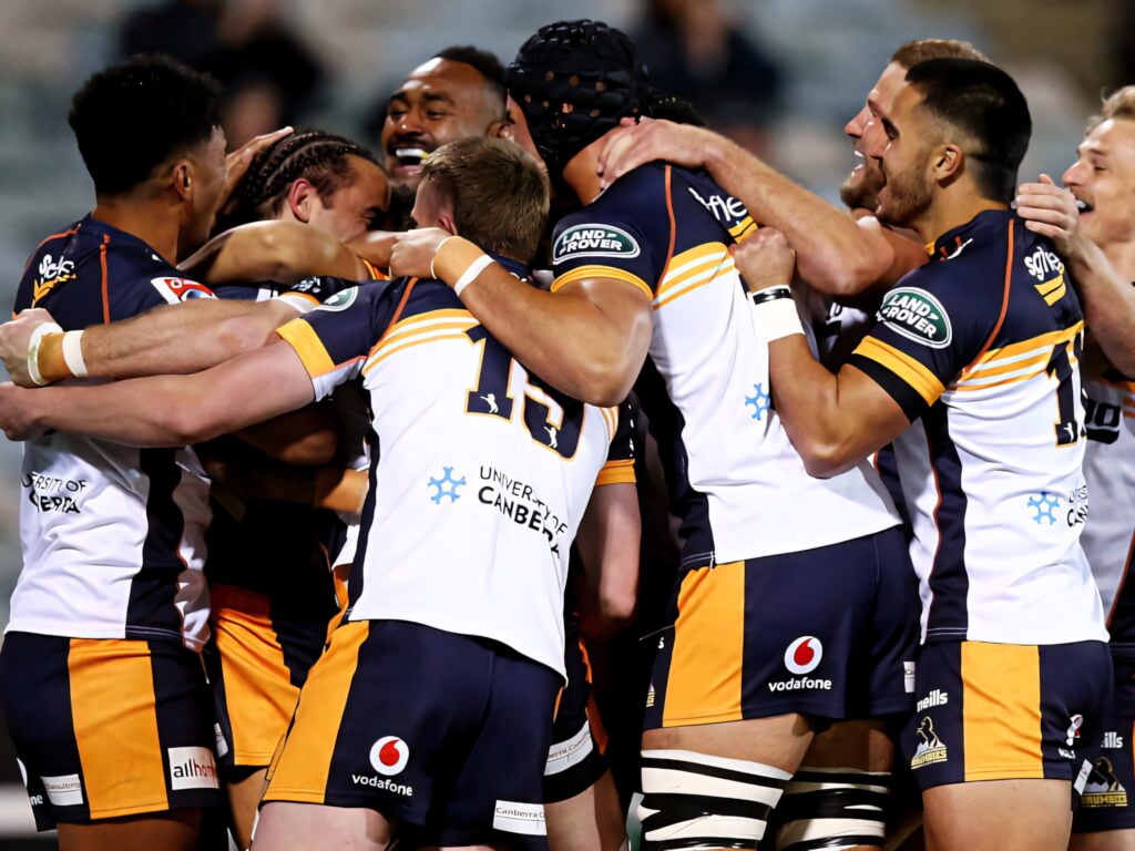 ACT Brumbies rugby players in white navy uniforms celebrating team huddle energetic sportsmanship wallpaper background