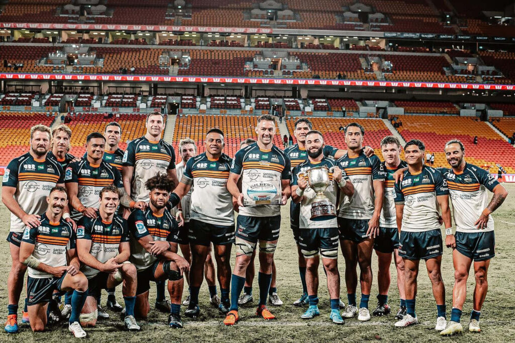 ACT Brumbies team in blue and gold celebrating victory on rugby field vibrant stadium wallpaper