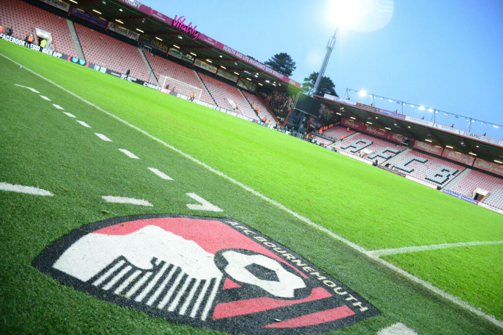 Vibrant AFC Bournemouth Logo Wallpaper on Green Pitch Background