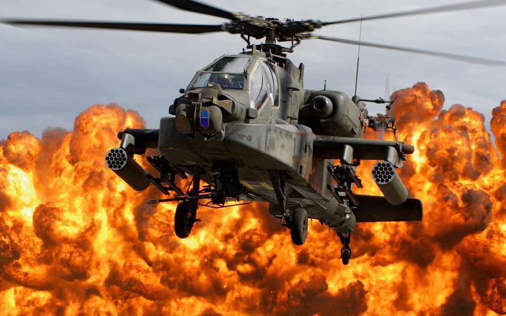 AH-64 Apache helicopter flying near fiery explosion intense military aviation wallpaper background