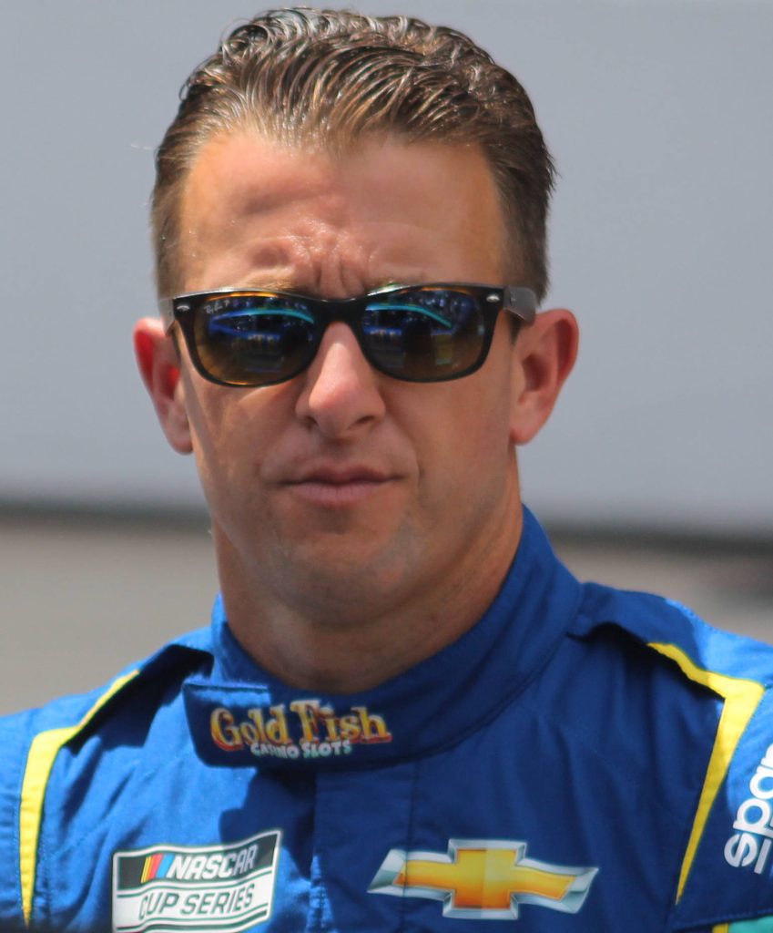 NASCAR driver AJ Allmendinger intense portrait in blue yellow racing suit with Chevrolet logos Wallpaper