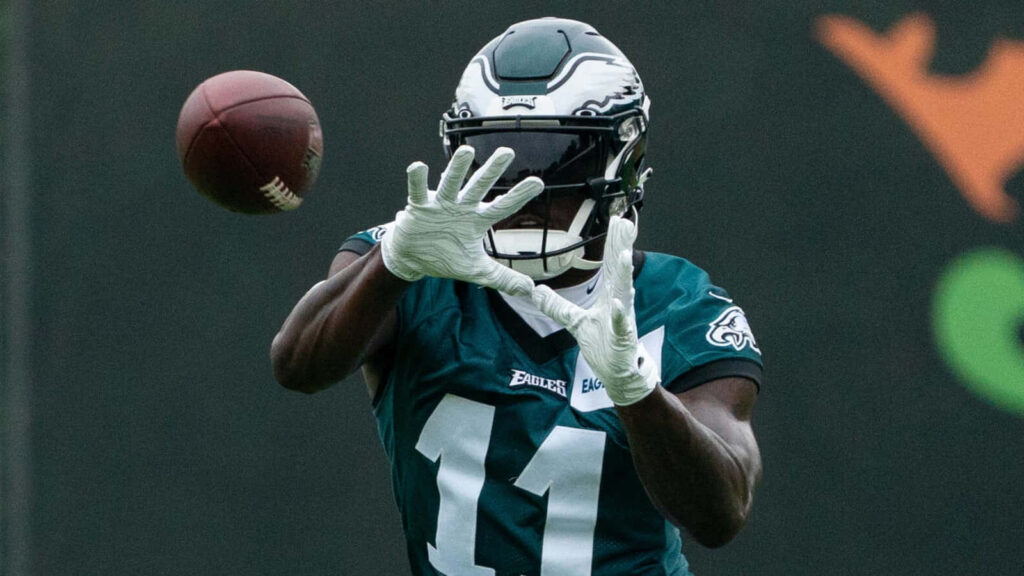 A J Brown catching football during Philadelphia Eagles practice wearing team uniform and gloves Wallpaper