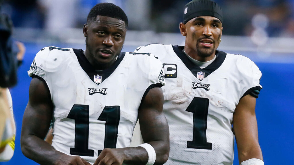 AJ Brown and teammate in white and green Eagles uniforms on field during intense NFL game Wallpaper