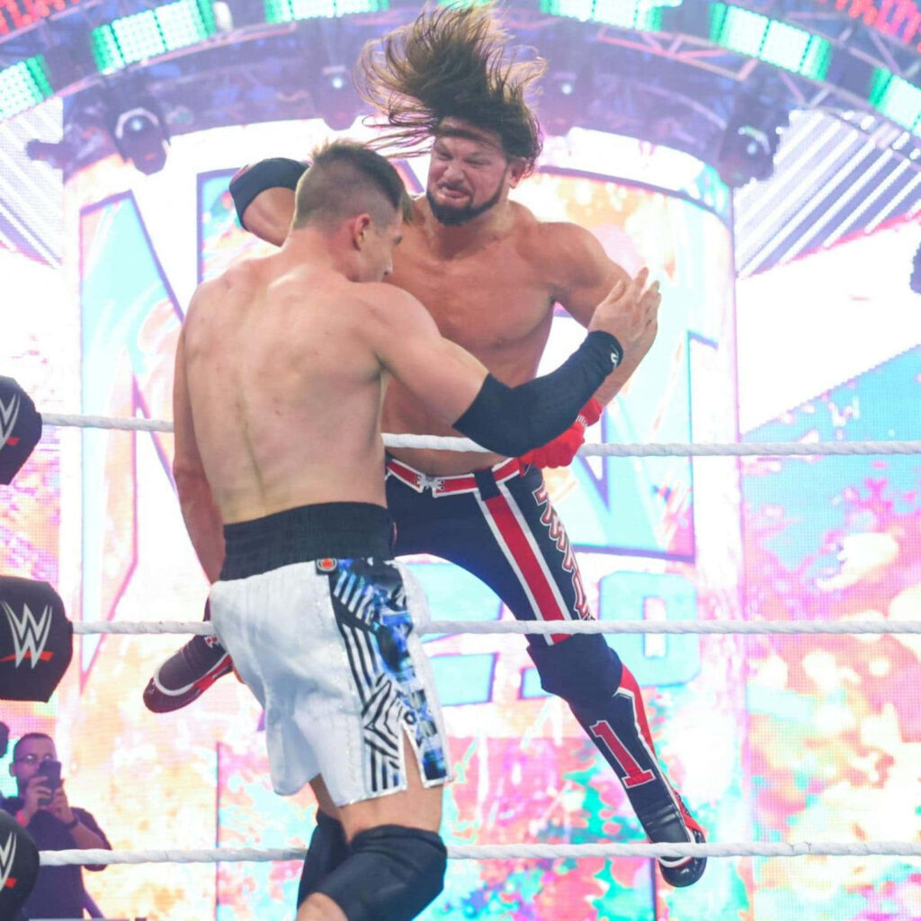AJ Styles performing a high-flying WWE wrestling move showcasing intense athleticism in ring Wallpaper