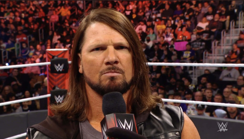 AJ Styles closeup in wrestling ring holding microphone with focused intense expression crowd background Wallpaper