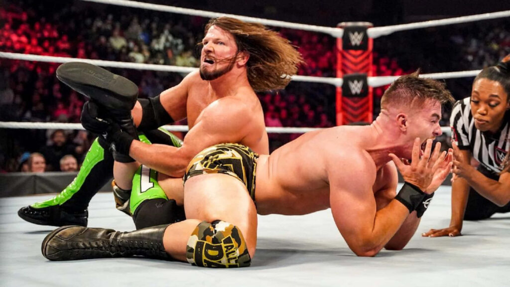 AJ Styles applies submission hold on Austin Theory in intense WWE wrestling match wallpaper background